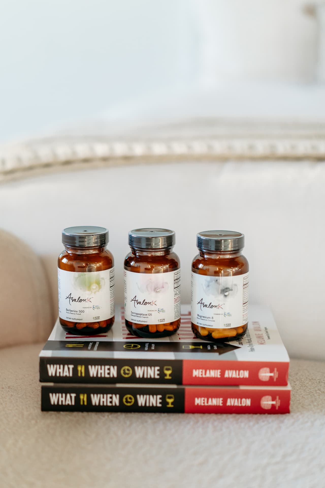 AvalonX supplement bottles resting on copies of Melanie Avalon's book What When Wine