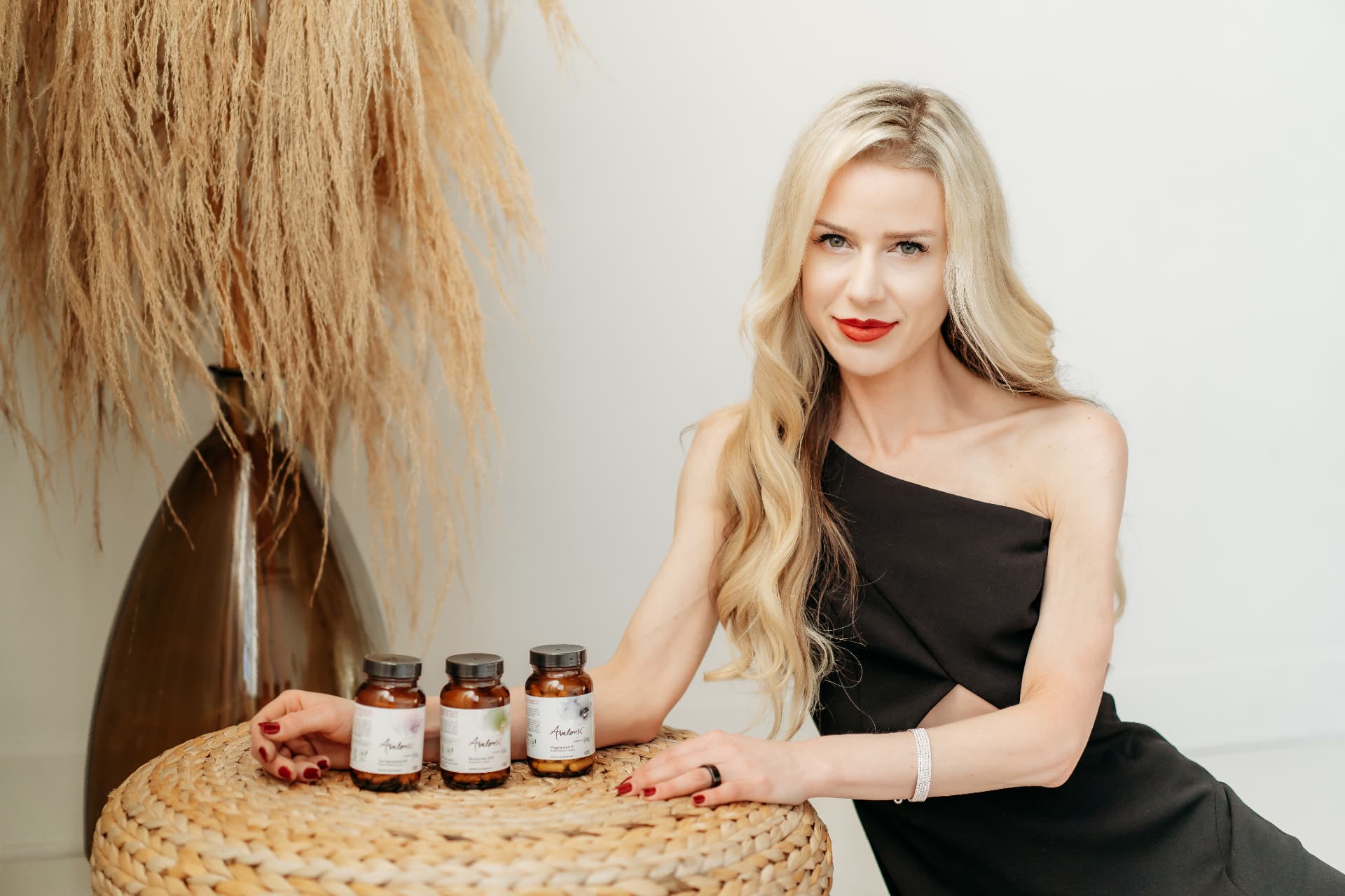 Melanie Avalon seated beside AvalonX supplement bottles in a bright, minimal room